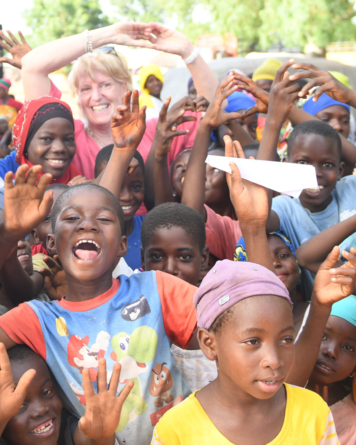 Le PDG de Plan International Canada avec un groupe d'enfants riant et applaudissant, les mains levées au-dessus de la tête