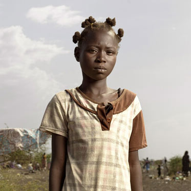 Jacklyn, 12, waits with her family for transport to Renk transit centre