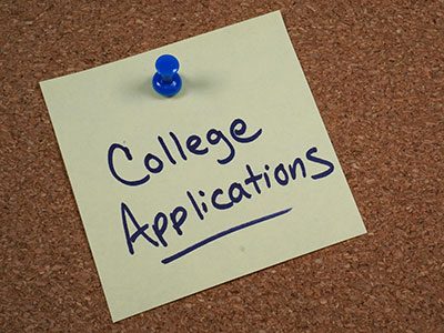 sticky note pinned on corkboard that says college applications