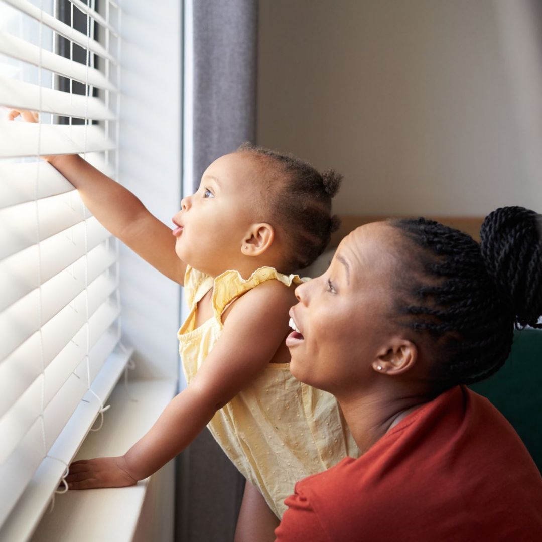 A woman and a baby look out a window