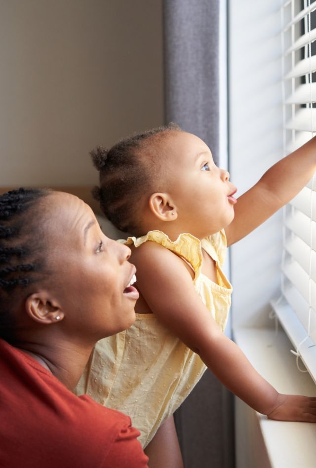 A woman and baby look out a window