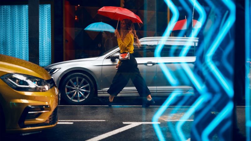 Eine Frau mit Regenschirm vor dem VW Passat