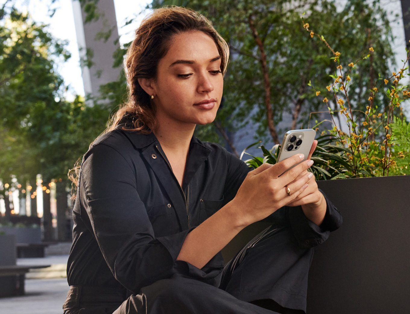 A smiling woman looking at the screen of an iPhone she's holding. 