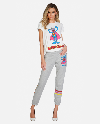 A model shows off matching leisure wear. The t-shirt features an illustraiton of Super Grover. The gray sweatpants have a matching illustration, with three horizontal stripes on the left pant leg.