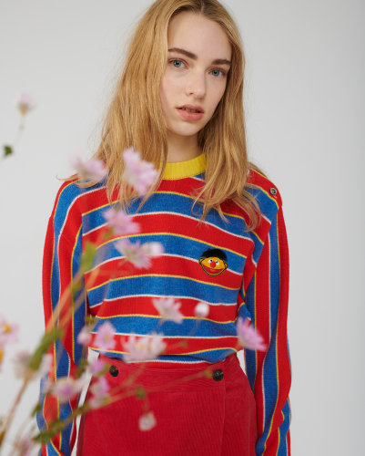 A model shows off a red and blue striped sweater embroidered with a tiny Ernie.