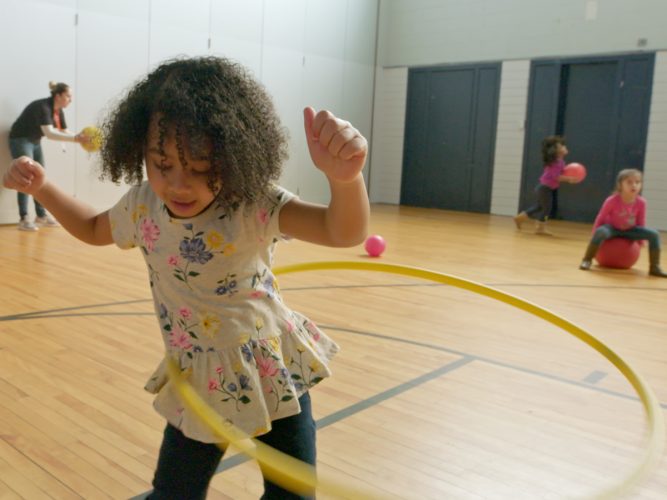 A child playing with a hula hoop.