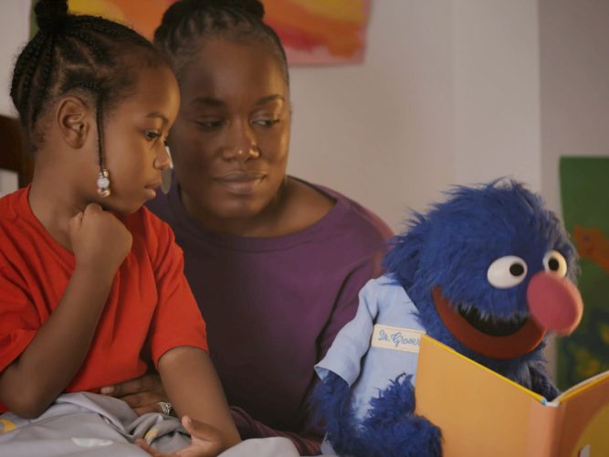 Grover reading to a family.