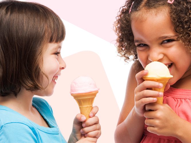 Two children giggle and eat ice cream