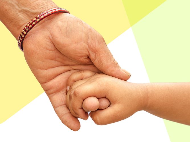 An adult hand holds a child's hand