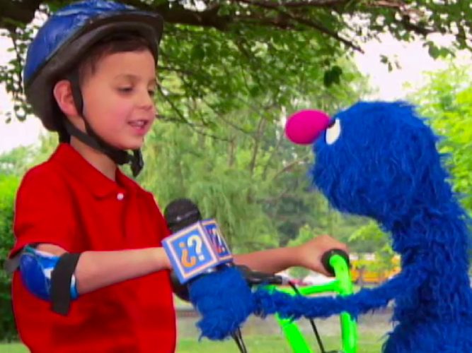 Grover interviews a child on a bike