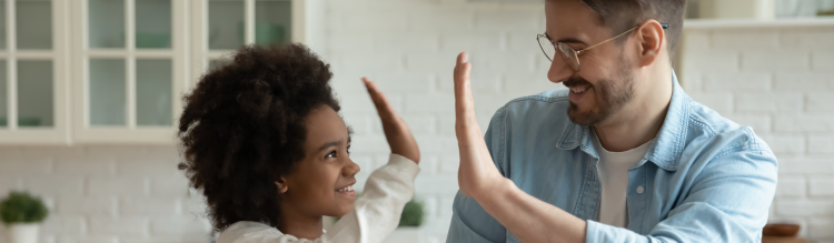 A smiling young girl high fives a father figure.