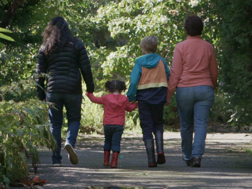 Two caregivers and two children walking.