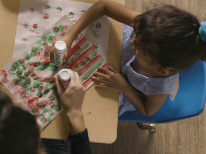 Child painting in a classroom.