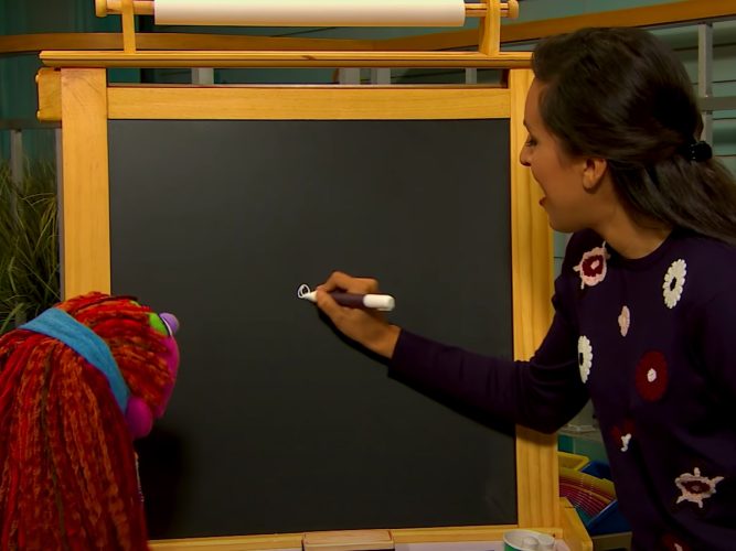 Sofía drawing on a chalkboard with Lily.