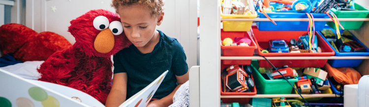 Elmo and a child read a book together.