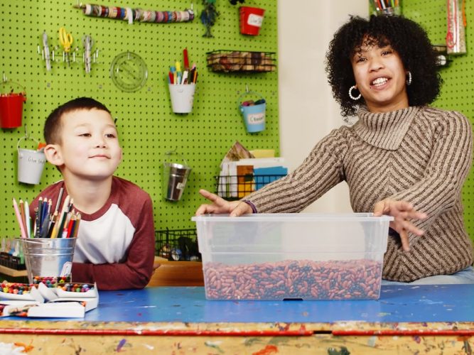 A grown-up and a child learn about sensory bins.