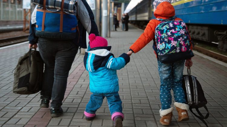 A parent with two kids walking in a train station depot.