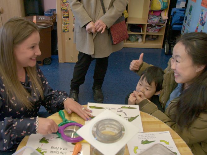 A parent and child talking to a teacher in a classroom.