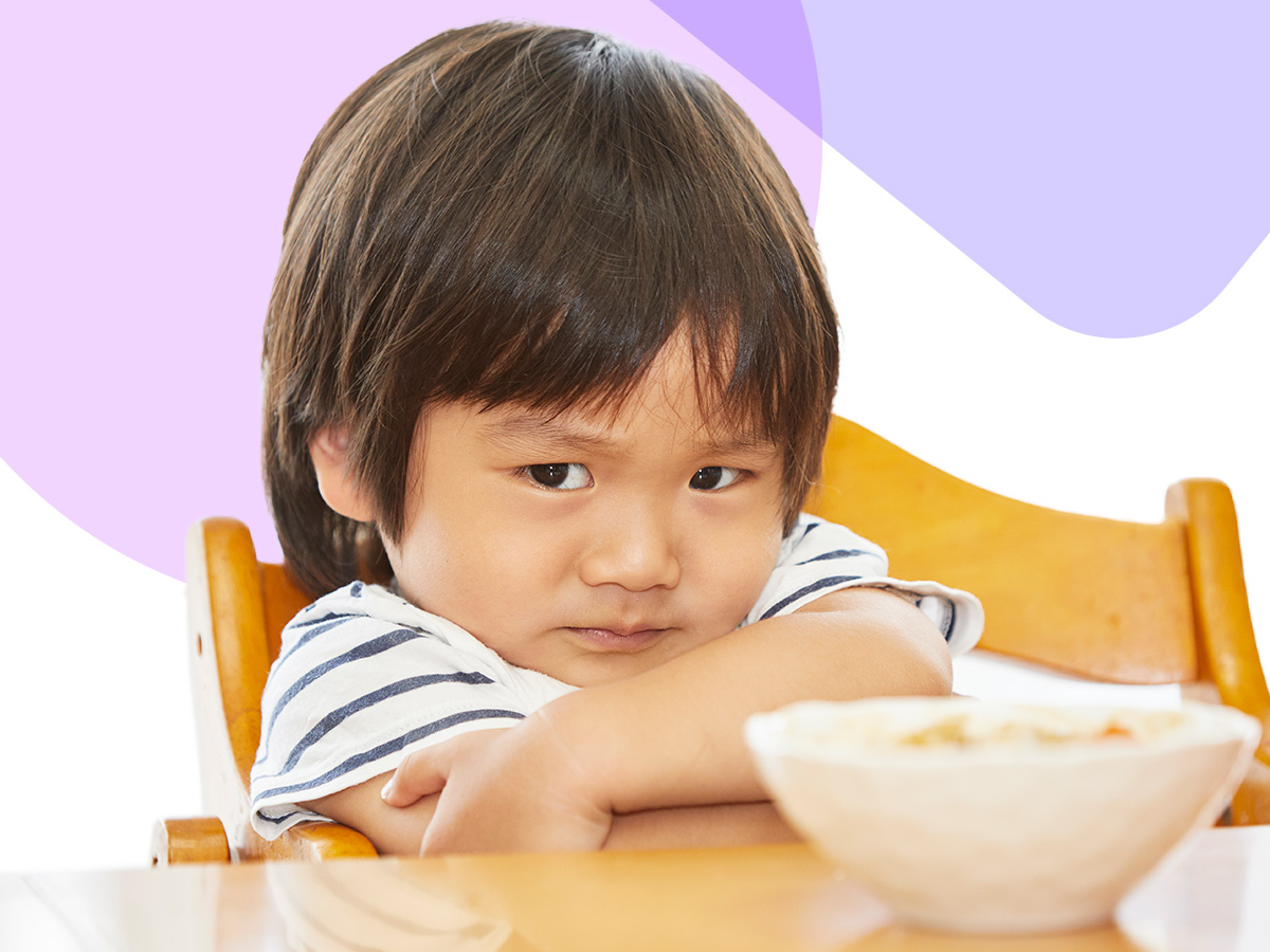 A frustrated child sitting in front of a bowl of food.