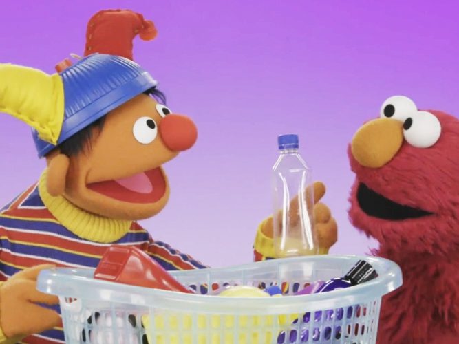 Ernie and Elmo with a basket of recycling.