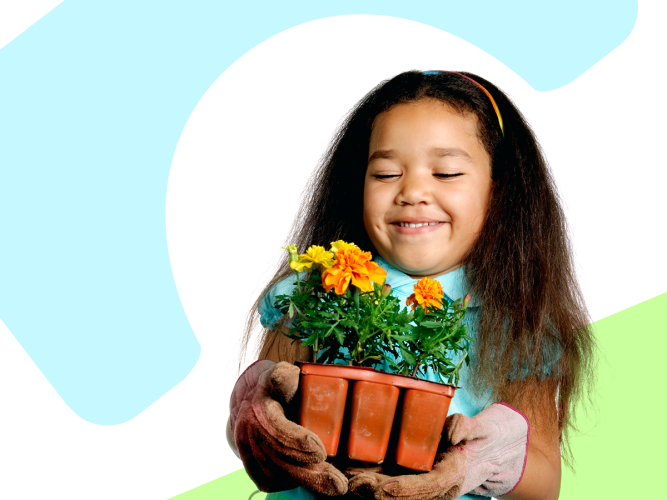 A child in gardening gloves holding flowers.