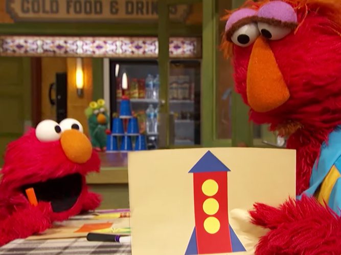 Elmo shows his dad his Arts and Crafts drawing.