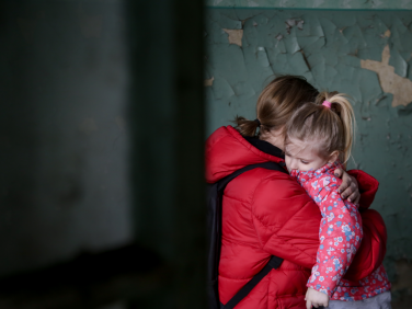 An adult holds a child in a comforting embrace.