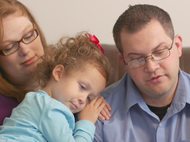 Two parents and a child on the couch.