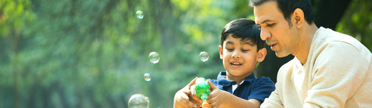 A father helps his son blow bubbles.