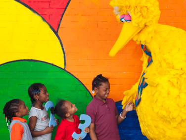 Big Bird greeting a group of kids.