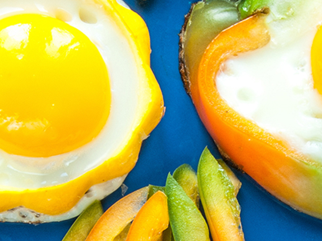 A blue plate with vegetables and sunny side up eggs