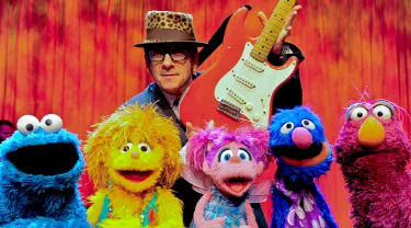 Elvis Costello with Cookie Monster, Kami, Abby, grover and Telly.