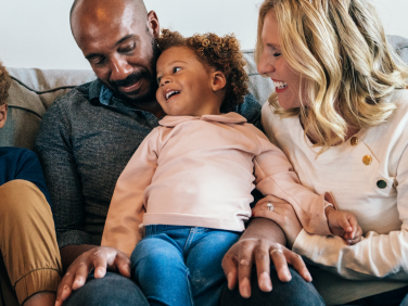 A family on the couch laughing with Elmo.