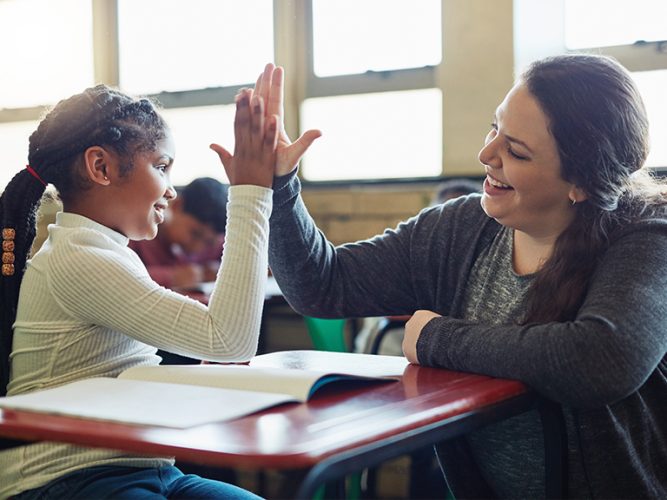 An adult high fives a child.