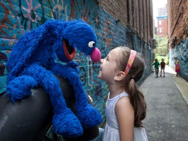 Grover and a young child touch noses.