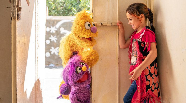 Basma and Jad in doorway with laughing child.