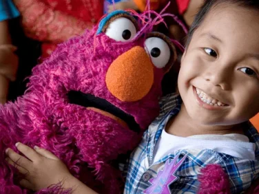 Telly Monster hugs a child.