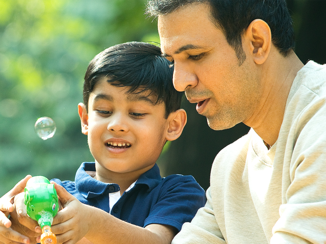 A child and their parent blowing bubbles