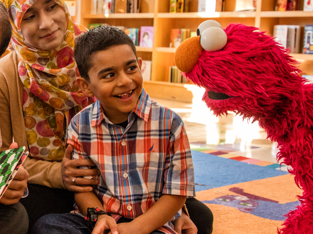 A family reading with Elmo at a library.