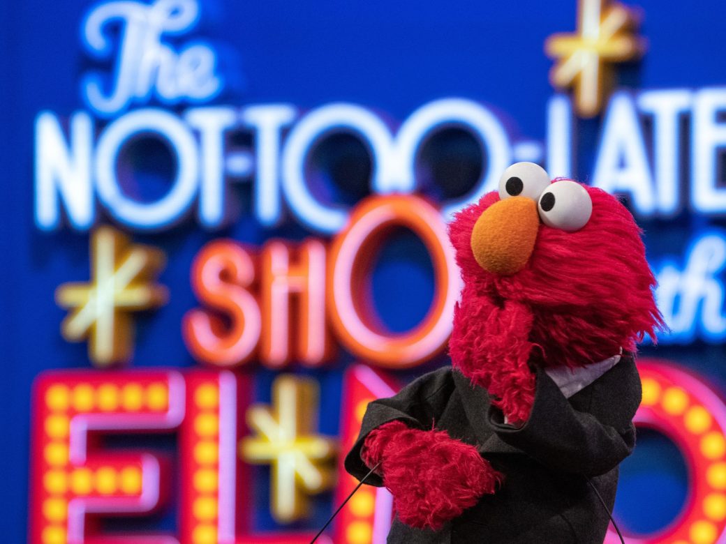 Elmo poses in a suit in front of The Not Too Late Show sign