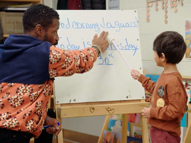 A teacher helps a child read a sentence