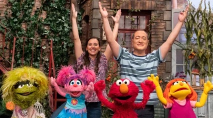 Nina and Alan join some Sesame Street muppets in stretching.