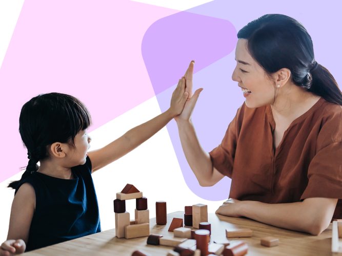 A caregiver and a child high five next to a tower of blocks.