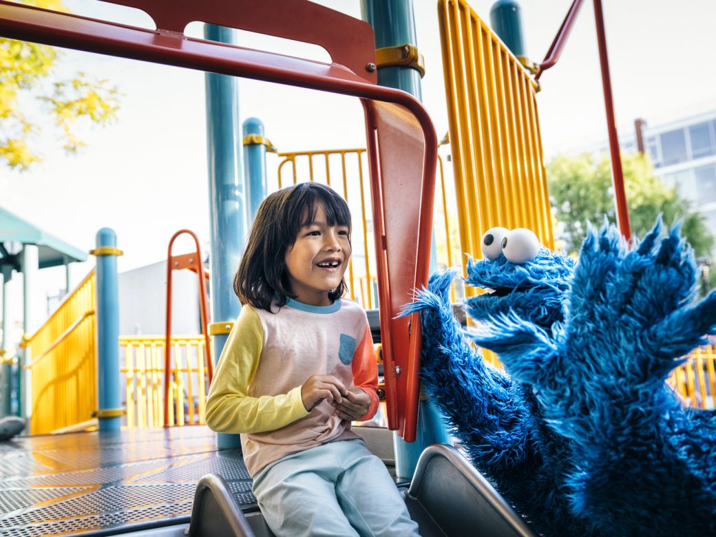 Cookie Monster plays with a child on a slide