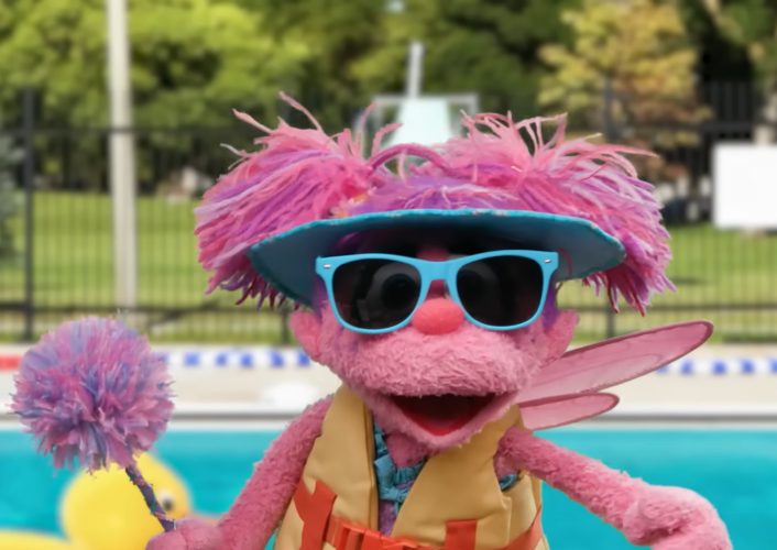 Abby smiles wearing sunglasses at the pool