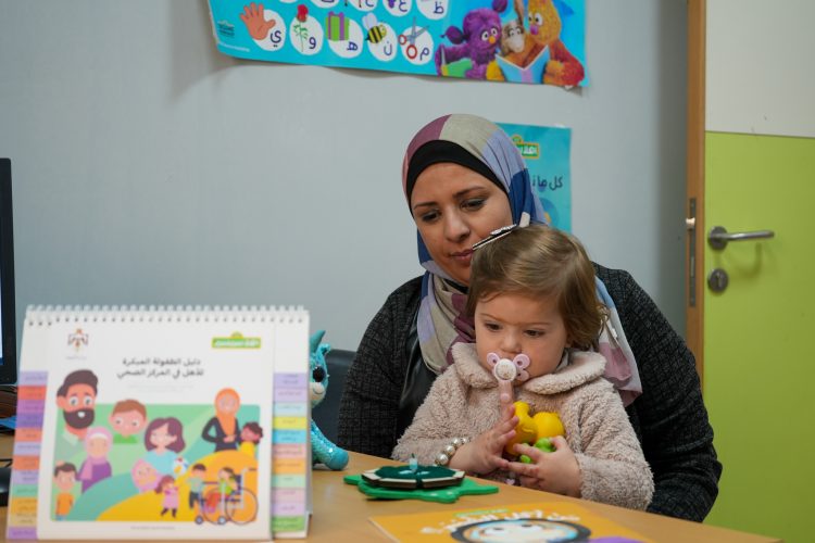 A parent sits with their child at a classroom table