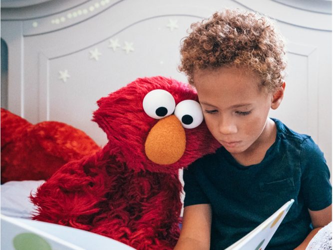 Elmo and a child reading together.