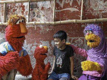 Elmo and his parents Louie and Mae talking to a child.