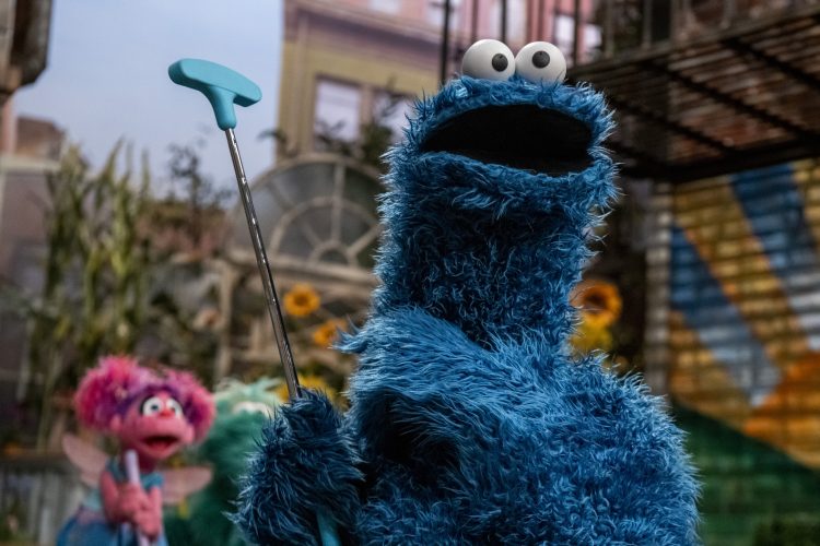 Cookie Monster holding a putting golf club.