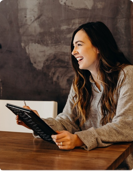 jeune femme souriante assise avec sa tablette numérique